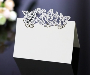 Detailed laser-cut butterfly wedding place cards with elegant white heart patterns