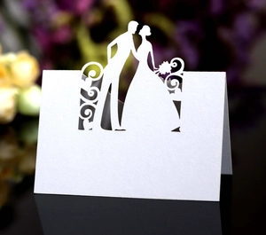 Detail of laser-cut pearl white wedding place card with bride and groom silhouette