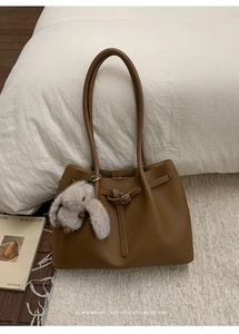 Detail of vintage brown pebble leather tote bag with plush rabbit charm and silver metal rings