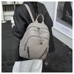 Close-up of grey litchi grain leather backpack with multi-zipper pockets and bell charms