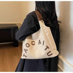 Close-up of retro canvas tote bag with brown leather straps and stitched letters