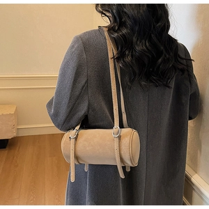 Detail of light beige cylinder shoulder bag showing fine leather texture and silver buckles