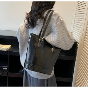 Detail of black oil wax leather bucket bag with glossy texture and adjustable metal buckle