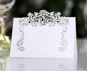 Detailed close-up of white laser-cut rose floral place card with mirror reflection