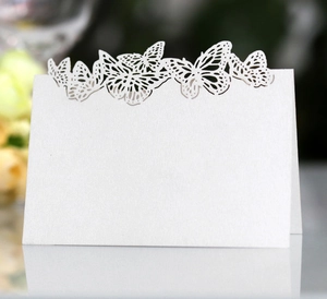Detail showing white laser-cut butterfly table card with elegant hollow pattern on paper