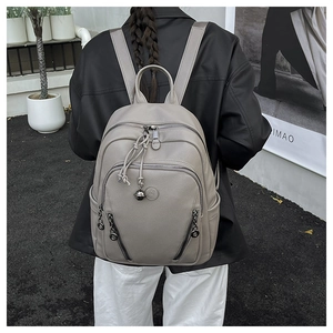 Close-up of taupe litchi texture backpack featuring metal zippers and soft leather finish