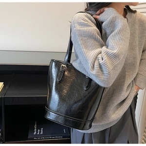 Close-up of black glossy patent leather texture and adjustable metal buckle on bucket bag