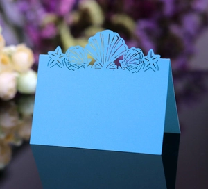 Detail of blue laser-cut place card with seashell and starfish motifs for wedding tables