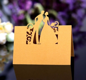 Close-up of golden laser-cut wedding place card with bride and groom silhouette