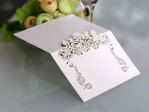 Detailed close-up of laser-cut rose patterns on elegant white pearlescent paper card