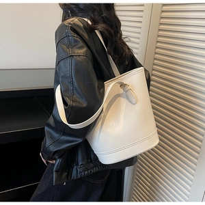 Detail of the white leather bucket bag showing adjustable metal buckles and side straps