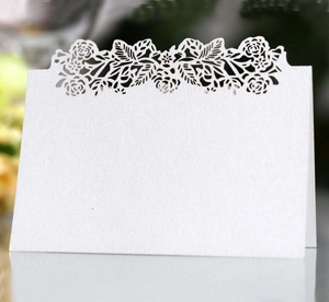 Detail of white laser-cut place card with elegant floral pattern for table decoration