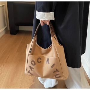 Detail of khaki canvas tote with embossed TAOCAITU leather letters and brown handles
