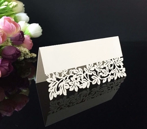 Macro detail of elegant laser-cut floral patterns on a white foldable wedding place card