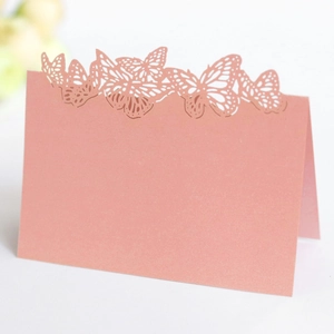 Close-up of laser-cut butterfly wedding place card in dusty rose pearlescent paper