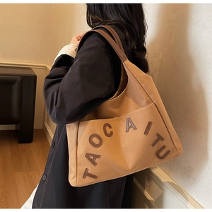Macro shot of large canvas tote bag with leather letter patches and reinforced strap