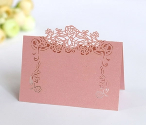 Close-up of laser-cut floral pink pearl paper place card for elegant wedding table settings