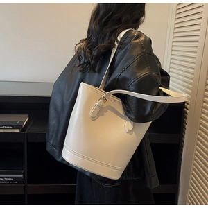 Creamy white leather bucket bag shown from a back view on a model with black jacket