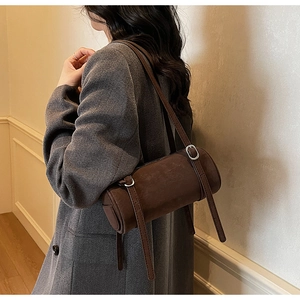 Detail of a dark brown barrel shoulder bag with adjustable silver metal buckles
