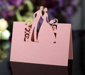 Macro detail of laser-cut wedding place card with bride and groom silhouette and pearl finish