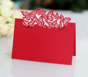 Detail of red laser-cut butterfly place card with elegant hollow design for weddings