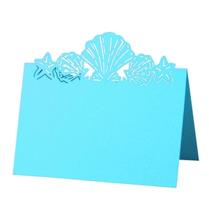 Close-up of laser-cut ocean shell and starfish patterns on sky blue table card