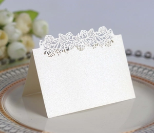 Close-up of laser-cut rose floral hollow design on white pearlescent wedding place card