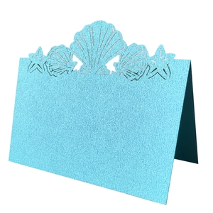 Macro detail of laser-cut seashells and starfish on light blue pearlescent place cards