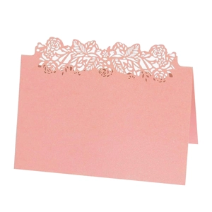 Close-up of laser-cut rose patterns on pink pearlescent paper wedding place cards