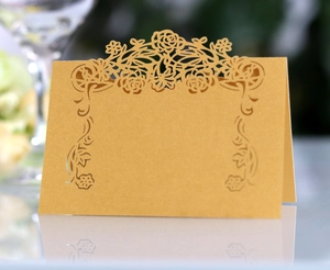 Detail of laser-cut hollow rose pattern on golden wedding place card cardstock