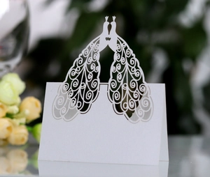 Detailed laser-cut white wedding place card featuring elegant peacock heart cutout designs