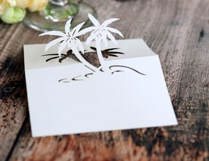 Detail of laser cut 3D white coconut tree place card for beach wedding table decor