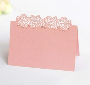 Detail of laser-cut flower hollow pattern on pink pearlescent paper table card