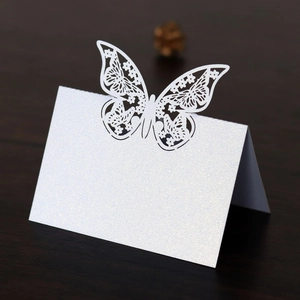 Detail of laser-cut butterfly place card with white pearlescent paper and floral texture