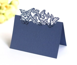 Detail of navy blue laser-cut butterfly place cards with intricate hollow floral patterns