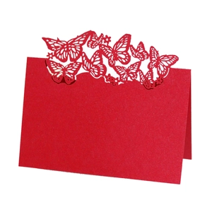 Detail of red laser-cut place card featuring intricate hollow butterfly patterns and folding design