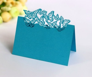 Detail of laser-cut peacock blue butterfly place cards for wedding table decoration