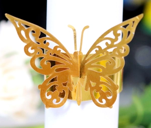 Close-up of golden butterfly napkin ring with laser-cut hollow pattern on white roll