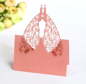 Macro view of laser-cut peacock pattern on pink peach wedding table place card