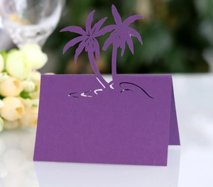 Detail of laser-cut purple place card with tropical coconut tree design for weddings