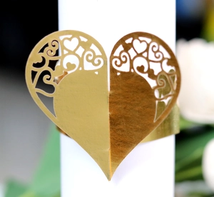 Detailed macro view of a gold hollow heart-shaped napkin ring with intricate lace texture