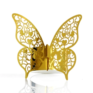Macro detail of laser-cut gold butterfly napkin ring with hollow heart patterns