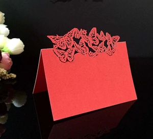 Detail of red laser-cut wedding place card featuring elegant butterfly silhouette