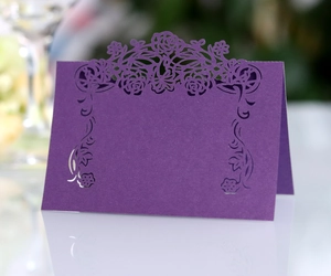Detail of purple laser-cut rose place card with elegant floral hollow design on mirror surface