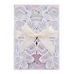 Elegant laser-cut white rose wedding invitation suite with cream silk bow and floral insert