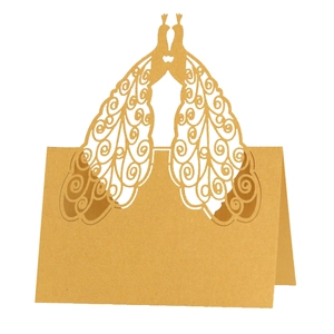 Detailed laser-cut golden peacock table card with intricate hollowed patterns