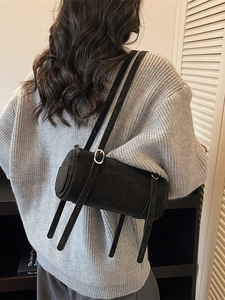 Minimalist black cylinder shoulder bag in matte suede texture with silver buckles