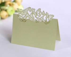 Detail of laser-cut butterfly and heart patterns on a pale green folded wedding place card