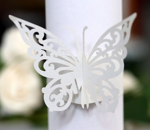 Macro detail of laser-cut white butterfly paper napkin ring with intricate floral patterns