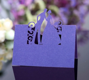 Detail of purple laser-cut wedding place card featuring a romantic groom and bride silhouette